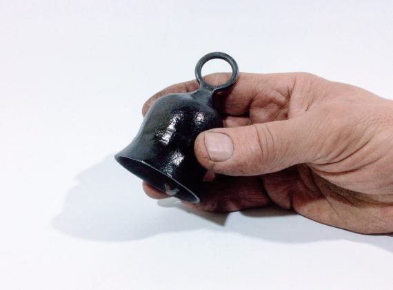 small hand forged steel bell held in hand