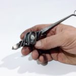 hand forged steel oddment approximately the length of a pen, incorporating a glass marble held in a twisted steel cage